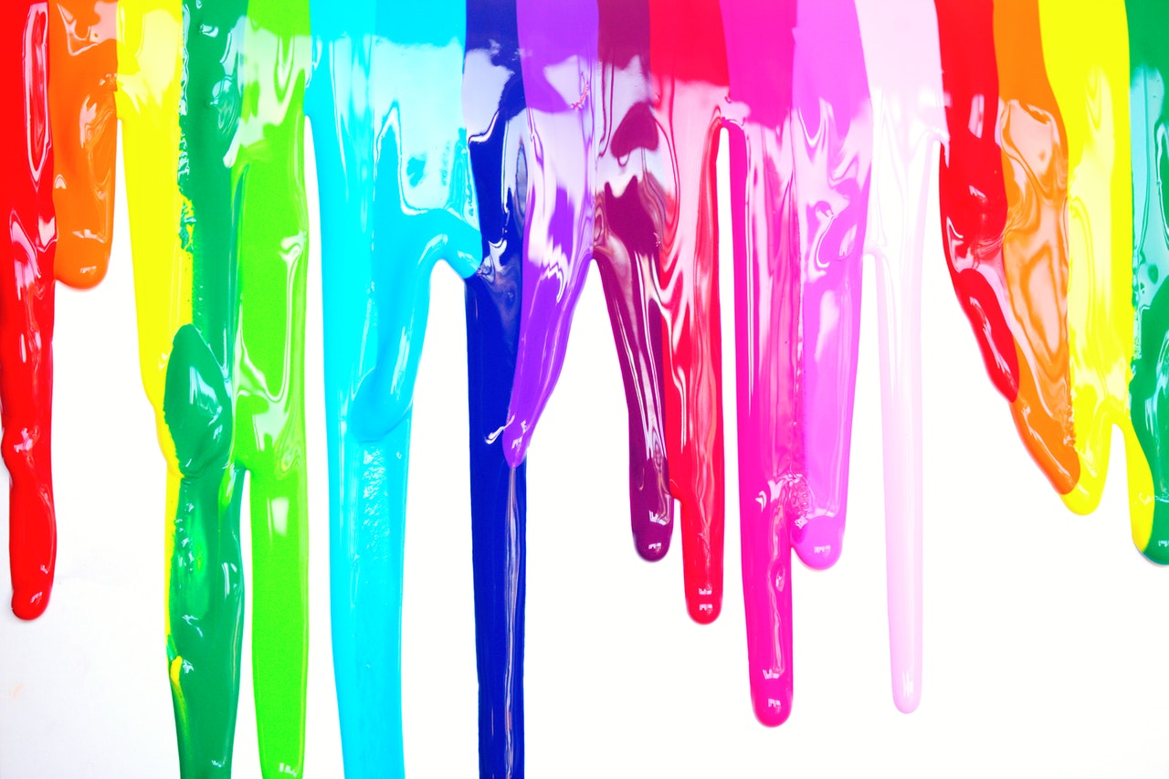 Various paints dripping down a wall.